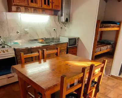 a kitchen with a wooden table with chairs and a sink at Brisas Serranas Departamentos in Villa Carlos Paz