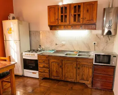 a kitchen with wooden cabinets and a white refrigerator at Brisas Serranas Departamentos in Villa Carlos Paz