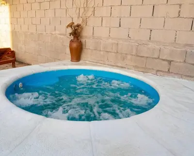 a bath tub filled with blue water next to a brick wall at Brisas Serranas Departamentos in Villa Carlos Paz