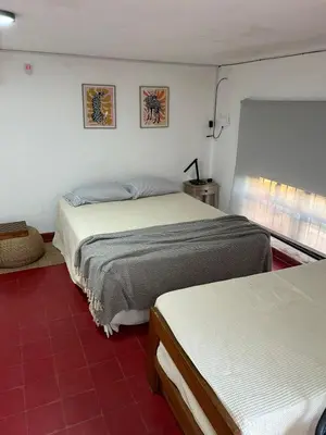 a bedroom with two beds and a red tile floor at Casa Henry in Cordoba