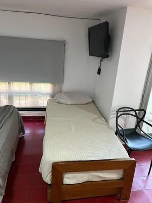 a small bedroom with a bed and a tv on the wall at Casa Henry in Cordoba