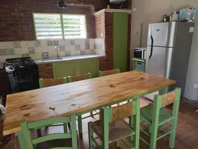 a kitchen with a wooden table with chairs and a refrigerator at La Maguada in Tanti
