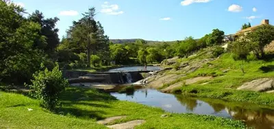 a river with a bridge in the middle of a field at La Maguada in Tanti