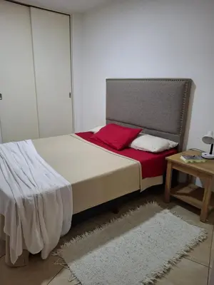 a bedroom with a bed with a red pillow and a table at Departamento en Nueva Cordobá, CORDOBA in Cordoba