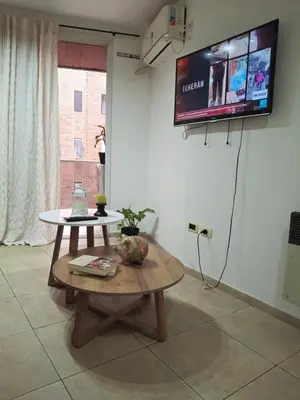 a living room with a table and a tv on the wall at Departamento en Nueva Cordobá, CORDOBA in Cordoba