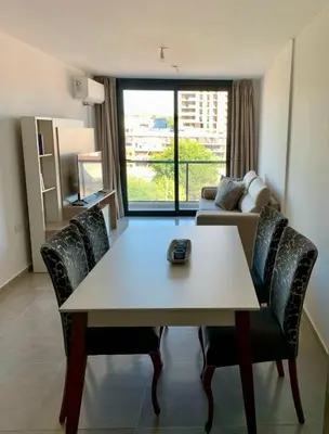 a living room with a table and chairs and a couch at Departamento en el centro de Carlos Paz con pileta in Villa Carlos Paz