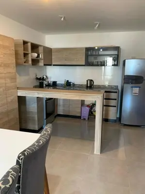 a kitchen with a table and a stainless steel refrigerator at Departamento en el centro de Carlos Paz con pileta in Villa Carlos Paz