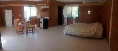 a bedroom with a bed and a table and a kitchen at Inambú in Villa Cura Brochero