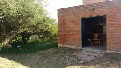a brick building with a doorway with a table and chairs at Inambú in Villa Cura Brochero