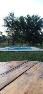 a wooden table in front of a swimming pool at Cabaña Benitto in Potrero de Garay