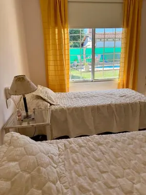 a bedroom with two beds and a table with a lamp at Casa Impecable, Piscina, Cochera, a 100 m del Lago, Familias in Villa Carlos Paz