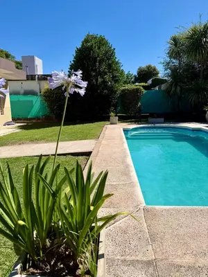 a flower is growing next to a swimming pool at Casa Impecable, Piscina, Cochera, a 100 m del Lago, Familias in Villa Carlos Paz
