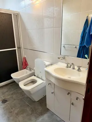 a white bathroom with a toilet and a sink at Casa Impecable, Piscina, Cochera, a 100 m del Lago, Familias in Villa Carlos Paz