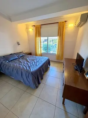 a bedroom with a bed and a desk and a laptop at Casa Impecable, Piscina, Cochera, a 100 m del Lago, Familias in Villa Carlos Paz
