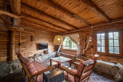 a living room with a table and chairs in a log cabin at Intihuasi Casa del Sol in Atos Pampa
