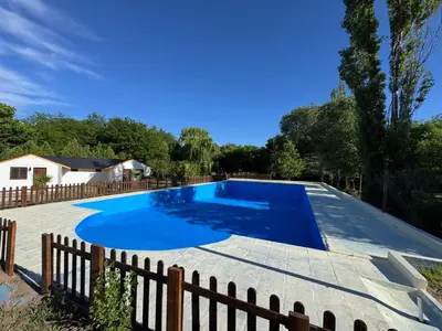 a large blue swimming pool with a wooden fence at Cabañas Gran Aldea in Mina Clavero
