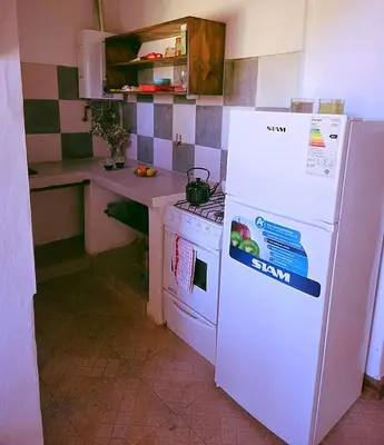 a kitchen with a white refrigerator and a stove at Cabañas Gran Aldea in Mina Clavero