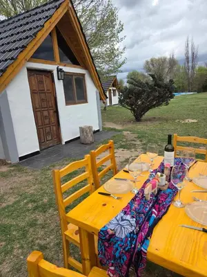 a wooden table with plates and wine glasses on it at Cabañas Gran Aldea in Mina Clavero