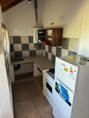 a kitchen with a white refrigerator and a stove at Cabañas Gran Aldea in Mina Clavero