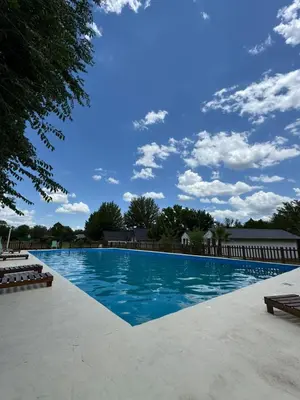 a large swimming pool with a blue sky with clouds at Cabañas Gran Aldea in Mina Clavero
