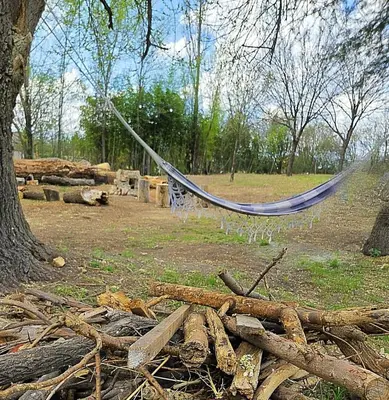 a hammock in a field next to a pile of logs at Cabañas Gran Aldea in Mina Clavero