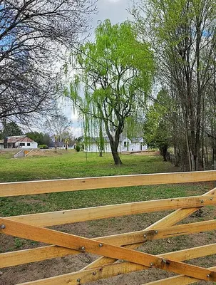 a wooden fence in a park with a tree at Cabañas Gran Aldea in Mina Clavero