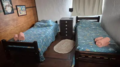 two twin beds in a bedroom with a dresser at La Insolente in Villa Yacanto