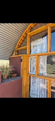 a window with a white curtain in a building at La Insolente in Villa Yacanto