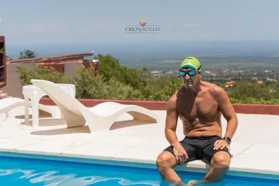a man sitting next to a swimming pool at Crepúsculo Serrano in Merlo