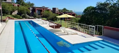 a large swimming pool with chairs and an umbrella at Crepúsculo Serrano in Merlo