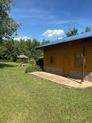 a small yellow building with a table and a umbrella at Las Casitas De Moni in Villa del Dique