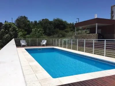a swimming pool with two chairs next to a fence at Complejo de Cabañas Coquena in San Antonio de Arredondo