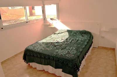 a bedroom with a green bed in a room with a window at Complejo de Cabañas Coquena in San Antonio de Arredondo