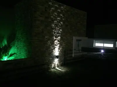 a building with a green light on the side of it at night at Complejo de Cabañas Coquena in San Antonio de Arredondo