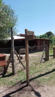 a wooden sign in front of a fence at Cabañas Solar de las Viñas in Villa Los Molinos