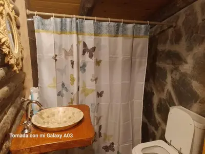 a bathroom with a shower curtain with butterflies on it at Cabañas Solar de las Viñas in Villa Los Molinos