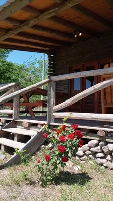 a wooden fence with a bunch of red flowers at Cabañas Solar de las Viñas in Villa Los Molinos