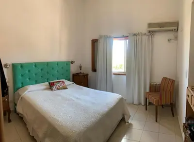 a bedroom with a bed with a green headboard and a window at Casa Maru in Villa Carlos Paz