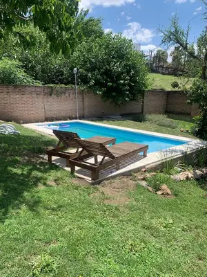 a wooden picnic table next to a swimming pool at Casa Maru in Villa Carlos Paz