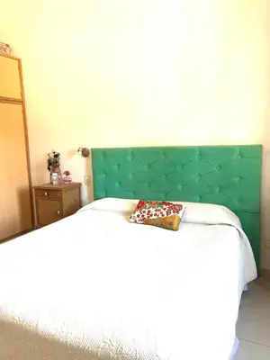 a bed with a green headboard with a pillow on it at Casa Maru in Villa Carlos Paz
