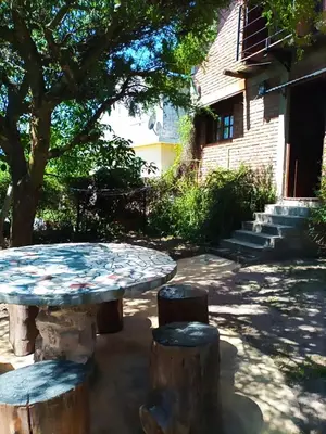 a table and two stools in front of a building at Caburé in Mina Clavero