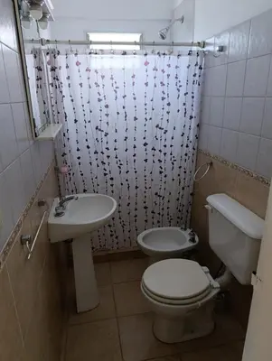 a bathroom with a sink and a toilet and a shower curtain at Balcones de Alberdi in Cordoba