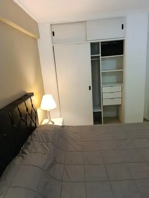 a bedroom with a bed with a lamp and a closet at Balcones de Alberdi in Cordoba