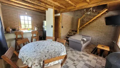 a living room with a table and a kitchen and a staircase at Cabañas Sacha Huasi in Travesía