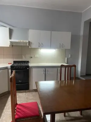 a kitchen with a table and a stove and white cabinets at Habitación Individual in Cordoba
