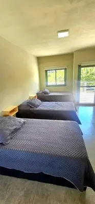 three beds are lined up in a room at Casa Privada Los Cardenales in Nono