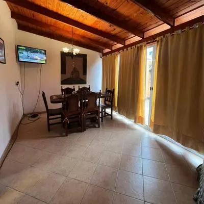 a dining room with a table and chairs and a television at Casa Expectacular cerca de la montaña in Villa Carlos Paz