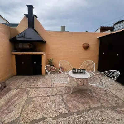 a patio with two chairs and a table and a stove at Casa Expectacular cerca de la montaña in Villa Carlos Paz