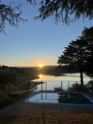 a sunset over a body of water with a swimming pool at Casa del lago los molinos in La Estancia
