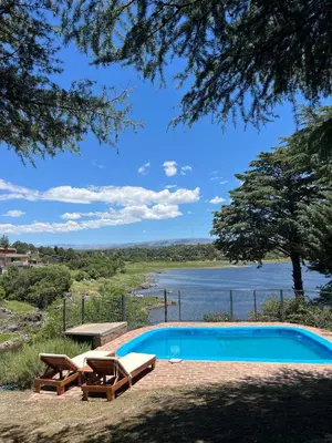 a swimming pool with two chairs and a picnic table next to a lake at Casa del lago los molinos in La Estancia